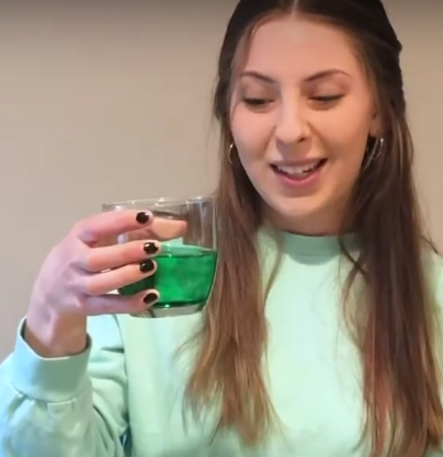 Anna holds a cup of water with green food coloring.