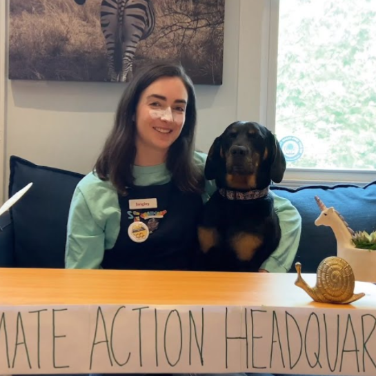 Langley sits behind a table. On the table is a sign that reads "Climate action headquarters"
