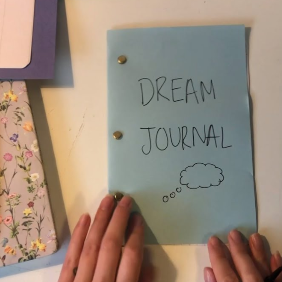 Anna writes "Dream Journal" on her handmade notepad.