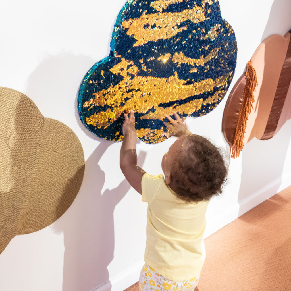 Toddler interacting with textured clouds in the Little Dreamers exhibit