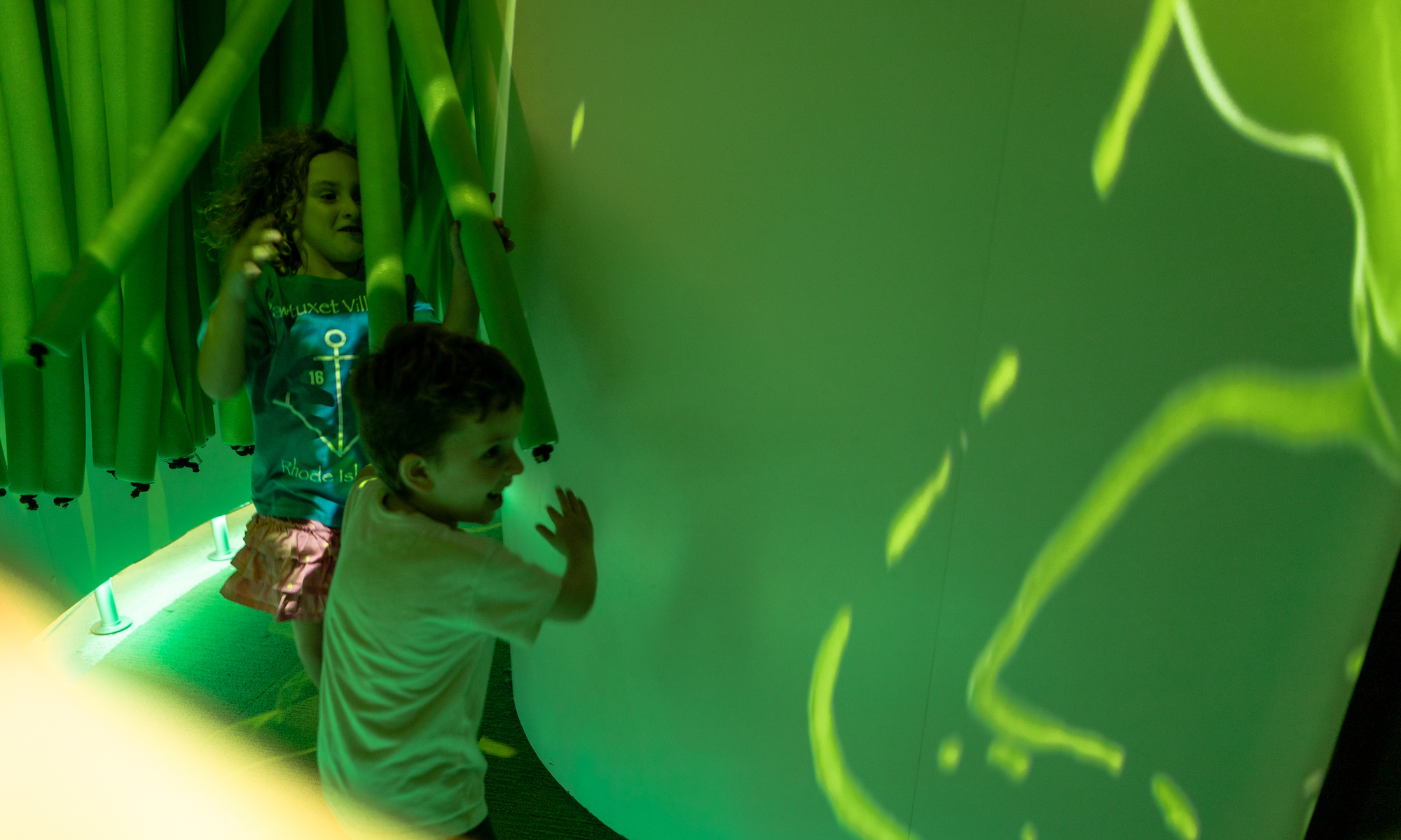 Two children running through the virtual slime room in the Art + Tech exhibit